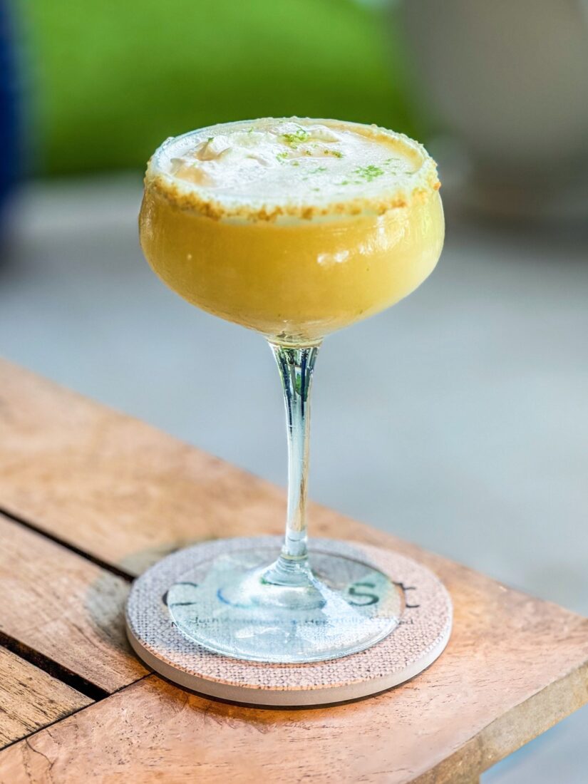 A yellow cocktail in a glass