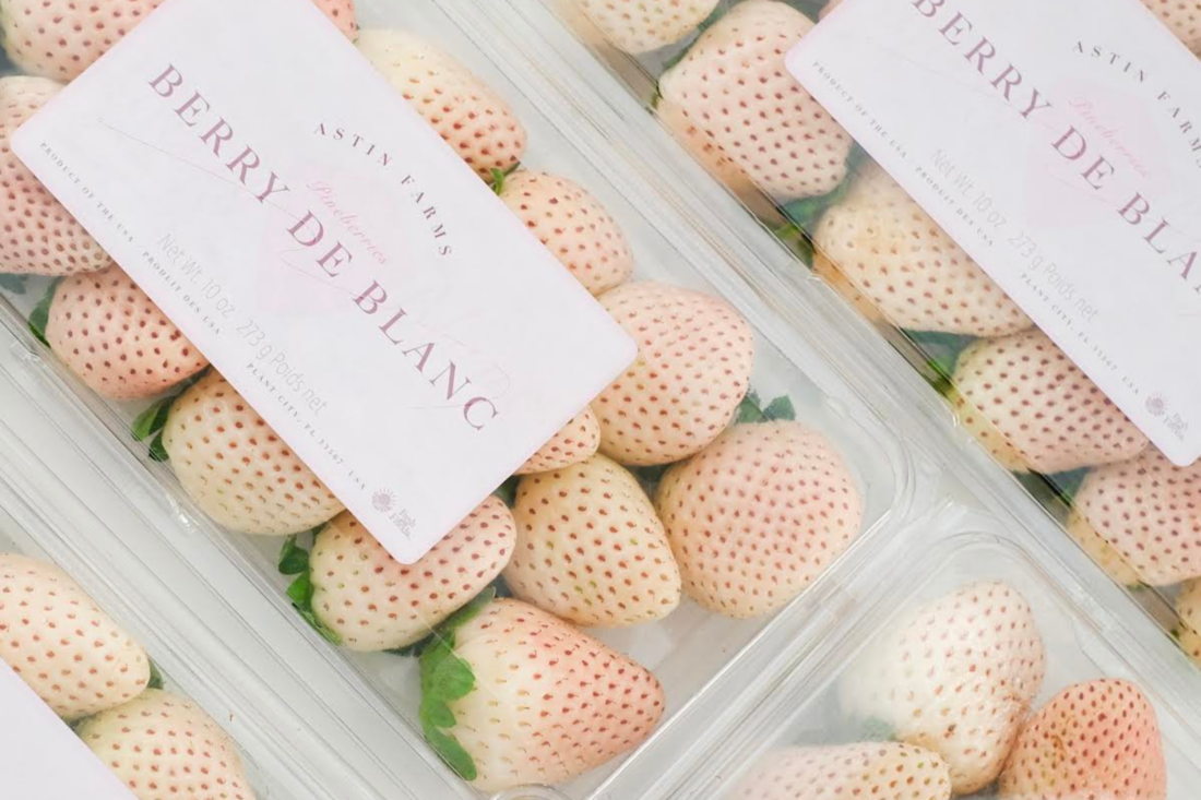 Containers of strawberries that are light pink and white