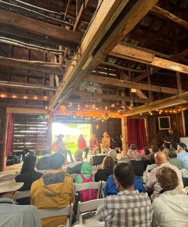 A crowd listening to ballad singers in a farm building