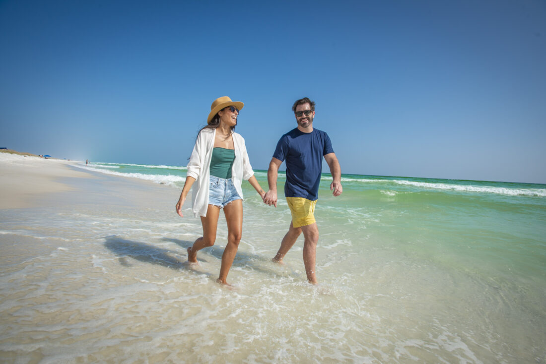 A couple holding hands walking on the beach