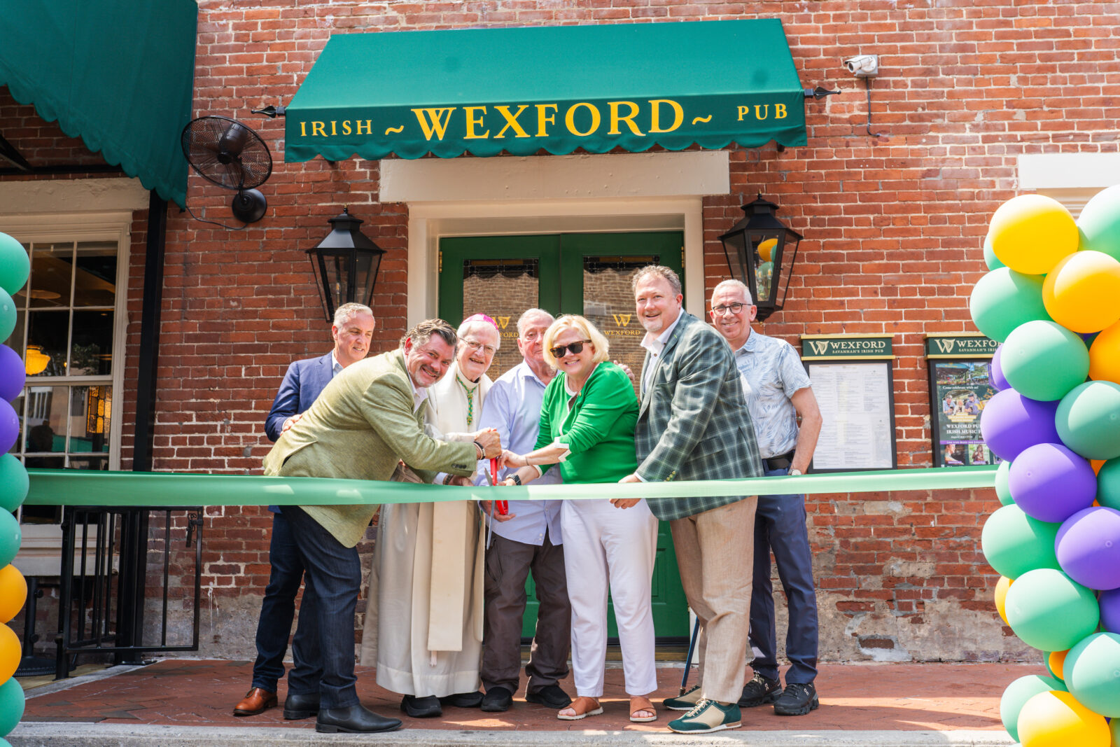 People cut a green ribbon outside a pub