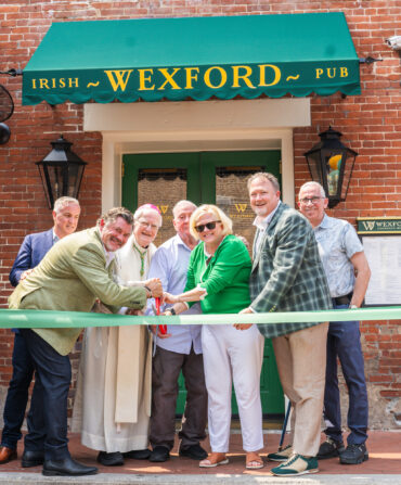 People cut a green ribbon outside a pub