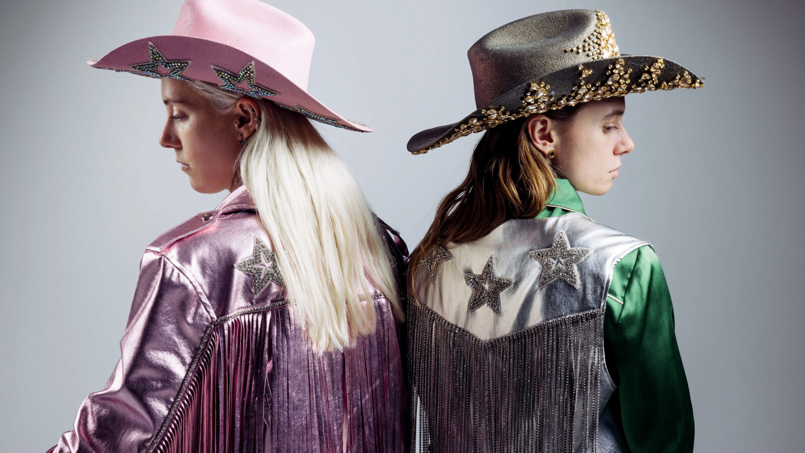 Two musicians in Western wear look over their shoulders