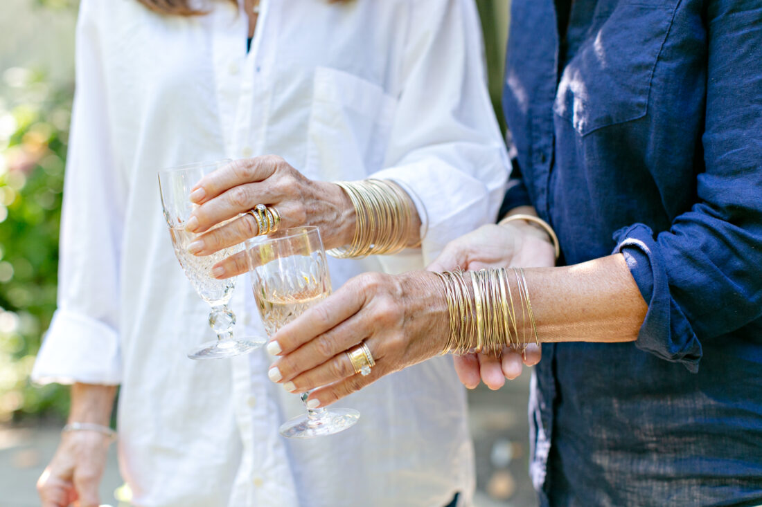 A detail of women's hands with gold bangles
