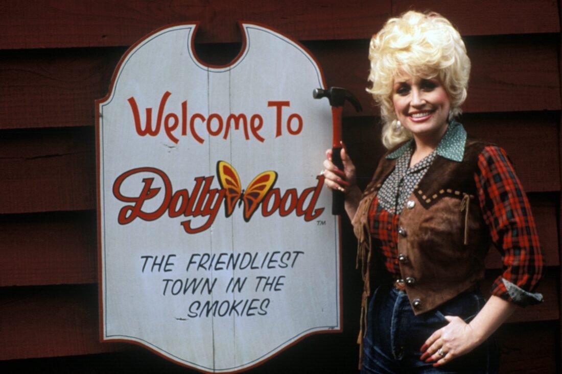 Dolly Parton poses next to a dollywood sign