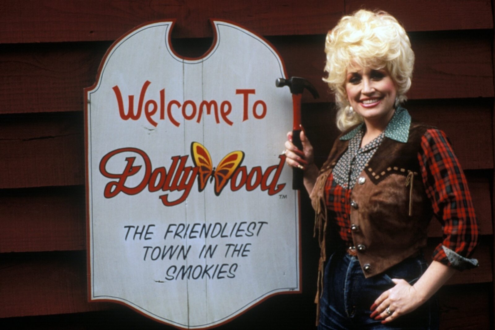 Dolly Parton poses next to a dollywood sign