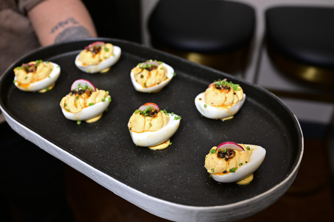 Deviled eggs garnished with Korean chili flakes, radish, and fried capers.
