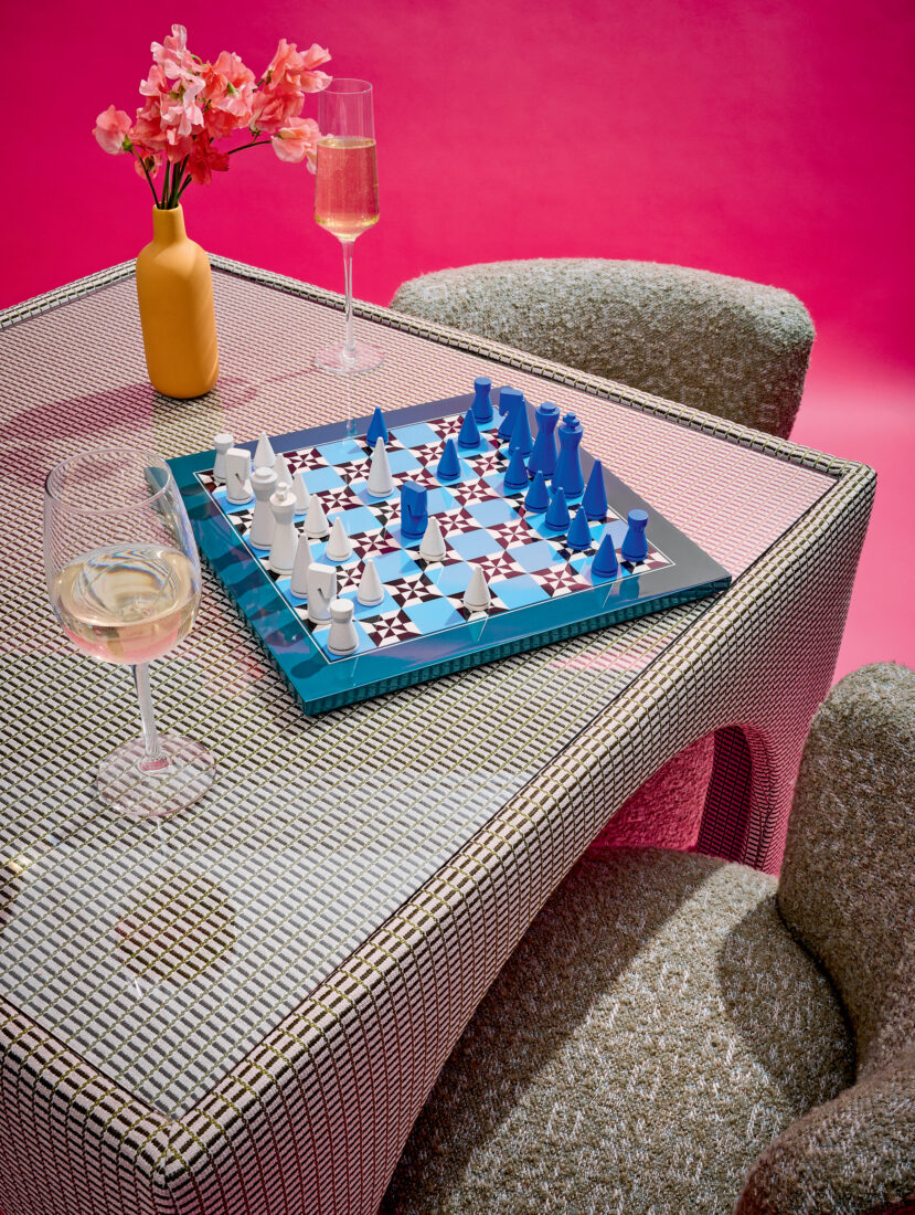 A blue chess board on a table against a pink background