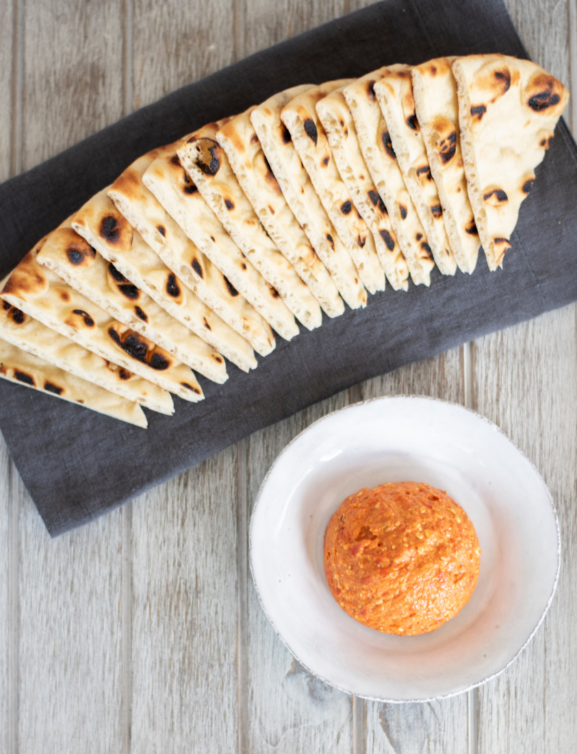 A tray of pita bread and a bowl of roasted red pepper spread