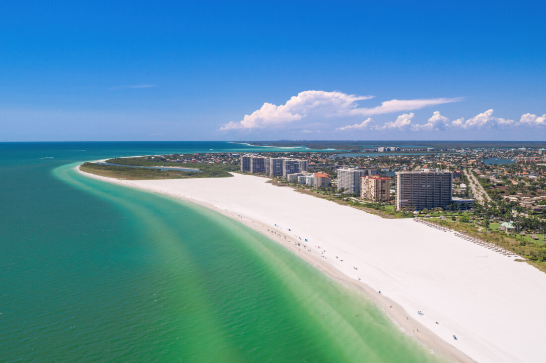 An aerial of a white sand beach and city skyline
