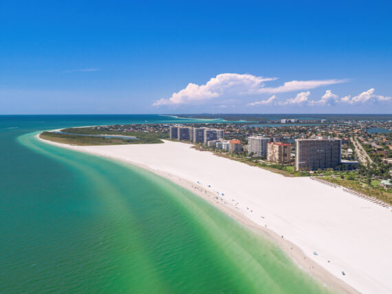 An aerial of a white sand beach and city skyline