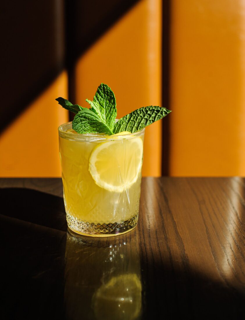 A cocktail garnished with mint and a lemon slice
