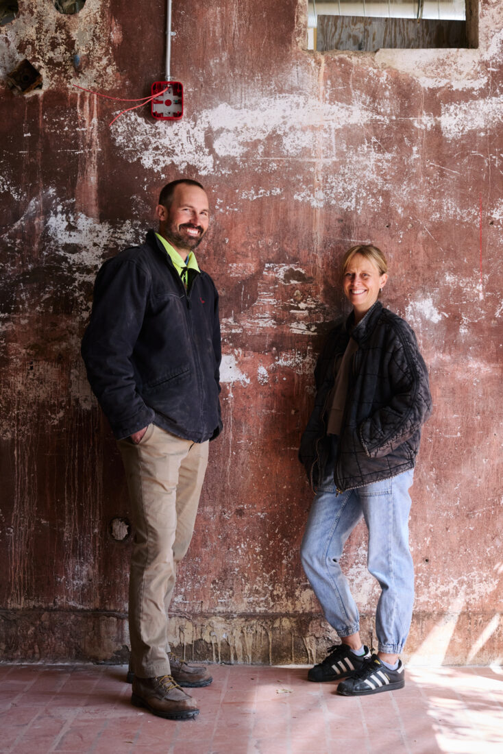 A man and woman standing in front of a distressed wall