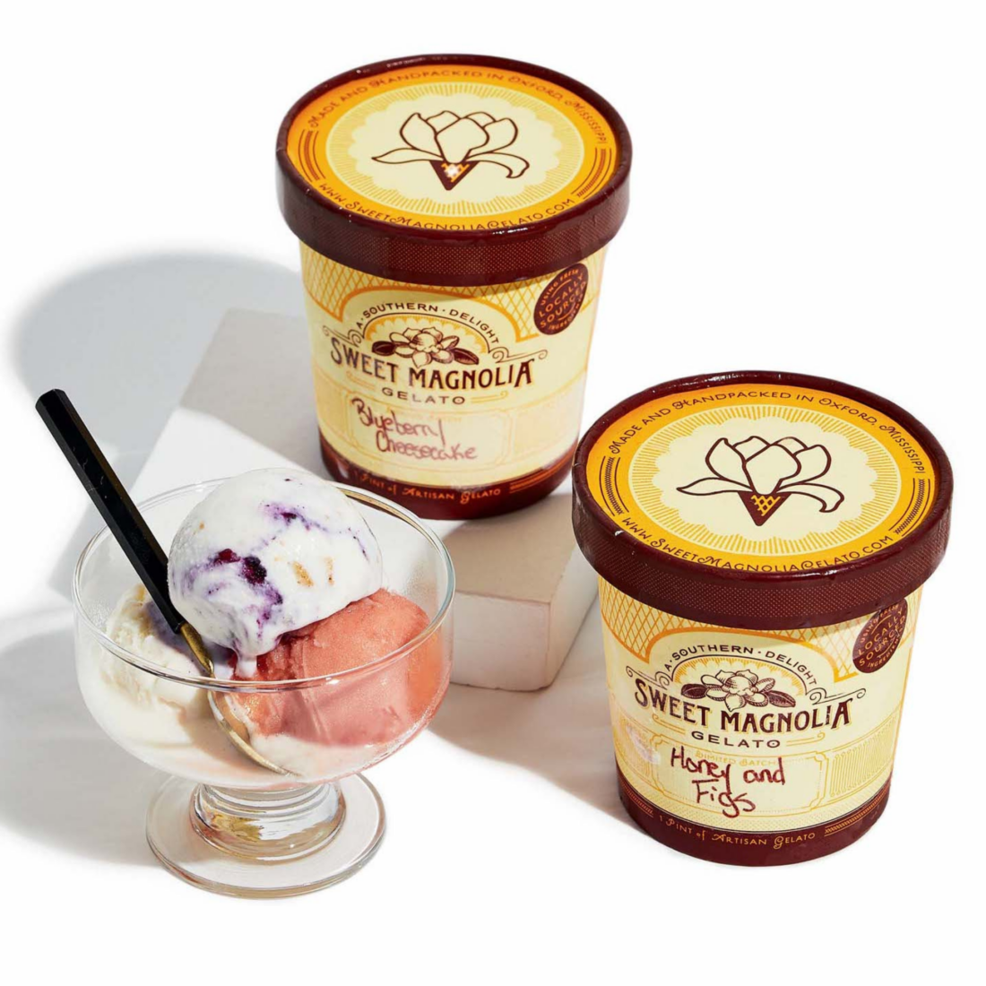 Pints of gelato beside a dish of gelato