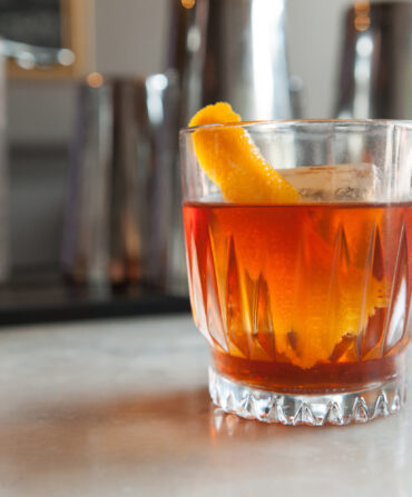 A glass of bourbon with an orange slice