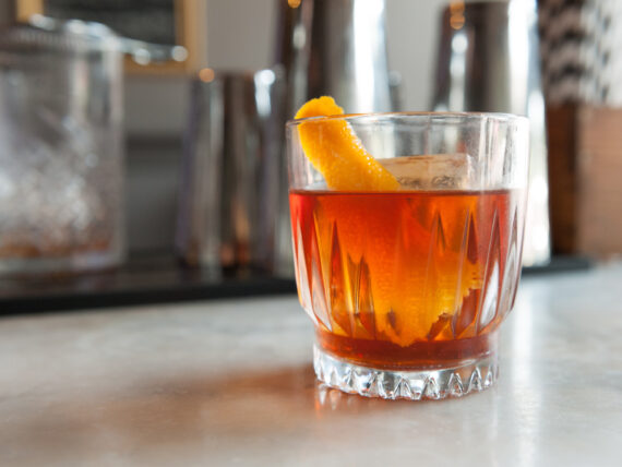 A glass of bourbon with an orange slice