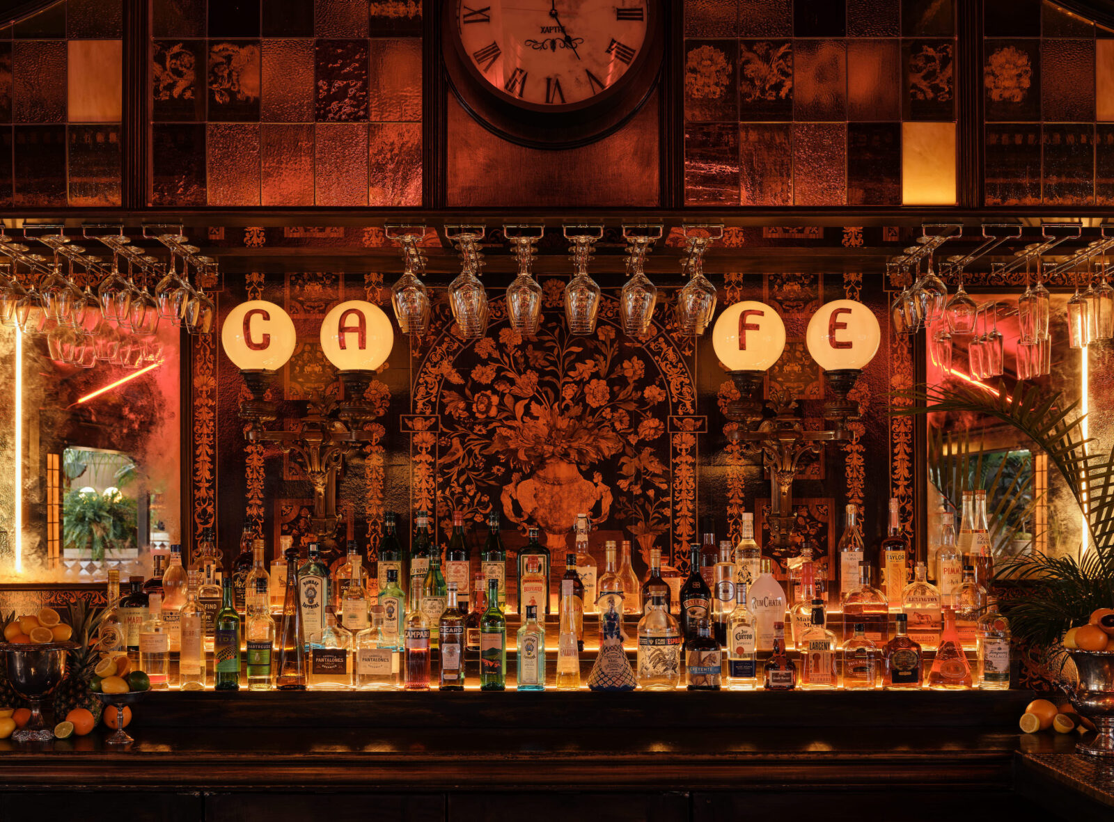 A bar with lacquered wallpaper in black and red and red lights. It also has pendant stained glass lights and panels and a stocked bar.