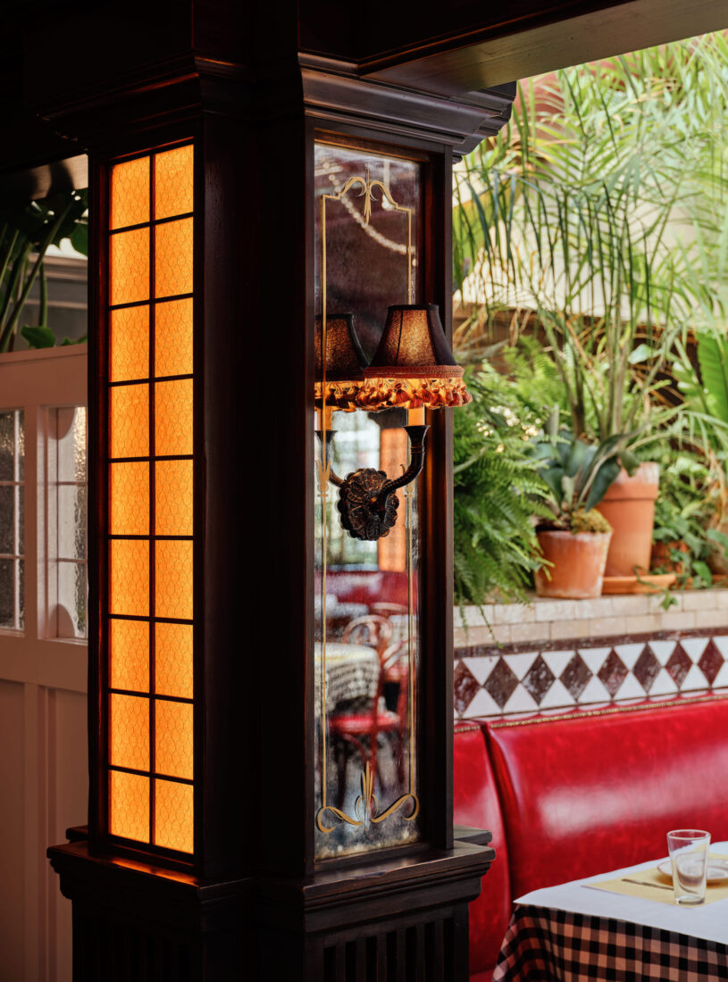A detail of window-paned columns by an outdoor booth with red leather