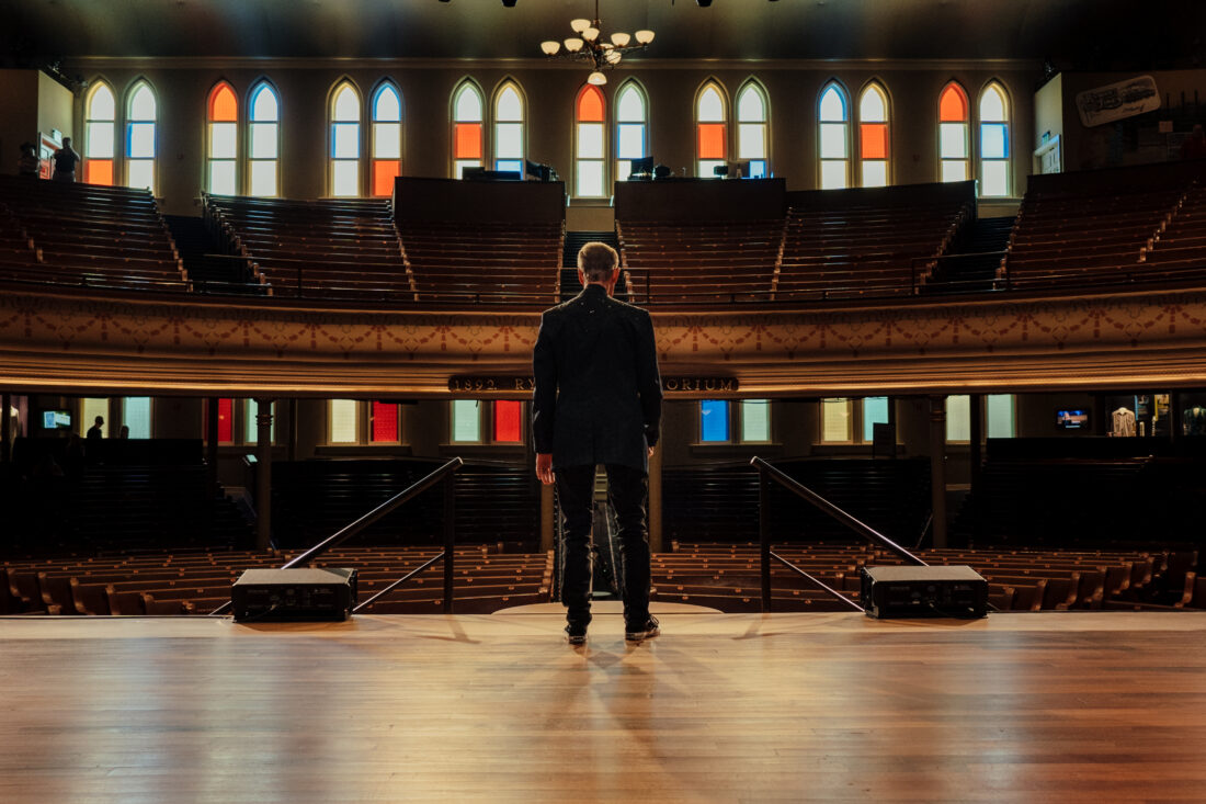 A man standing on a stage in an empty auditorium
