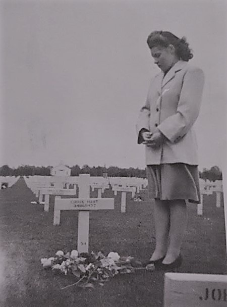 A black and white photo of a woman visiting a grave