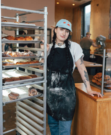 A woman stands by a rack of pastries