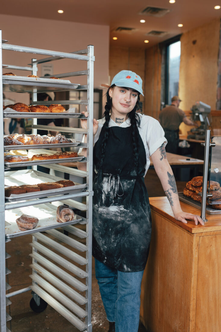 A woman stands by a rack of pastries