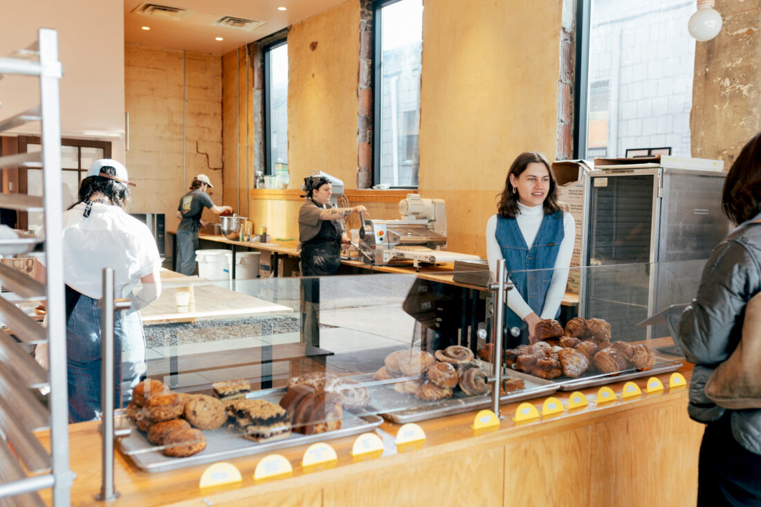 A woman at a pastry counter greets customers