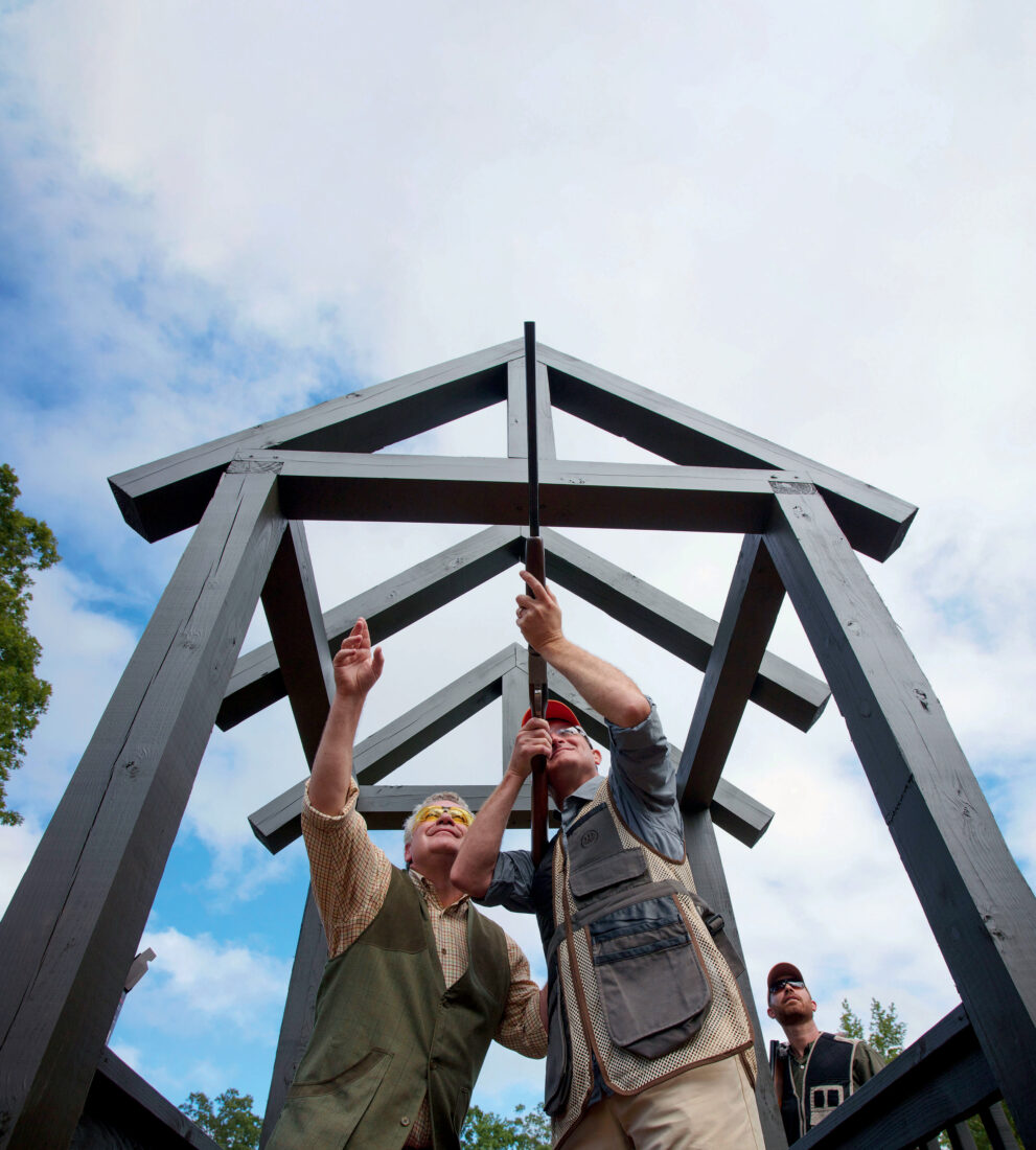 A pair of men aim a gun