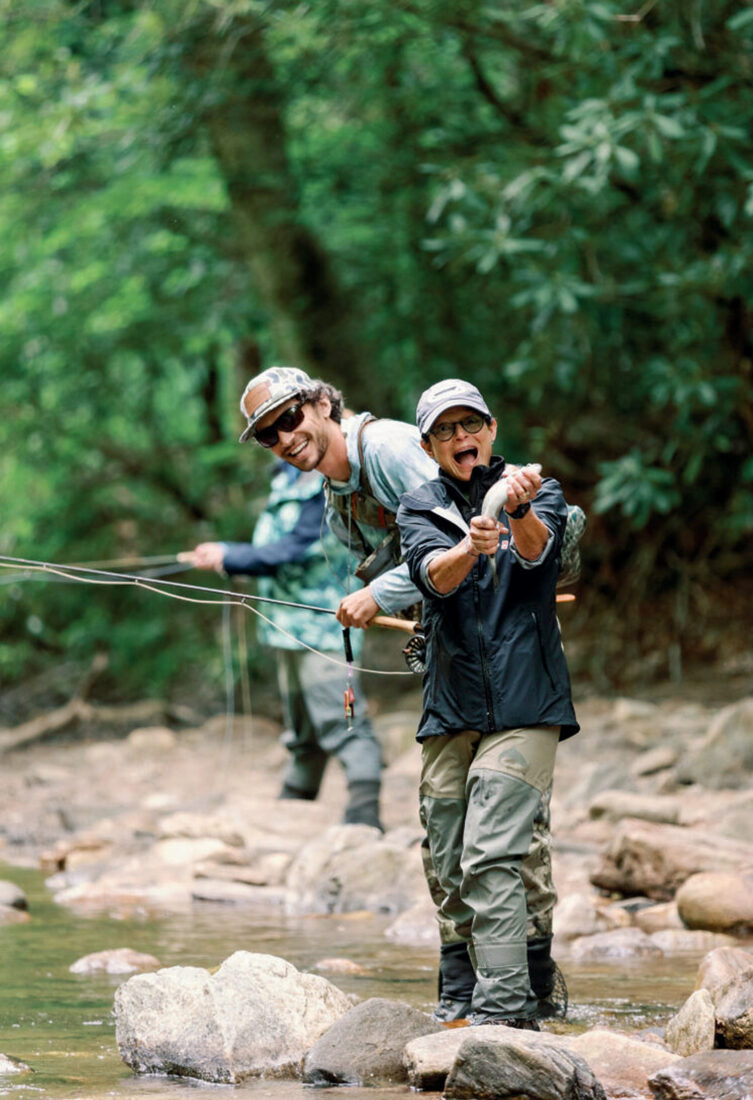 A boy catches a trout in a river