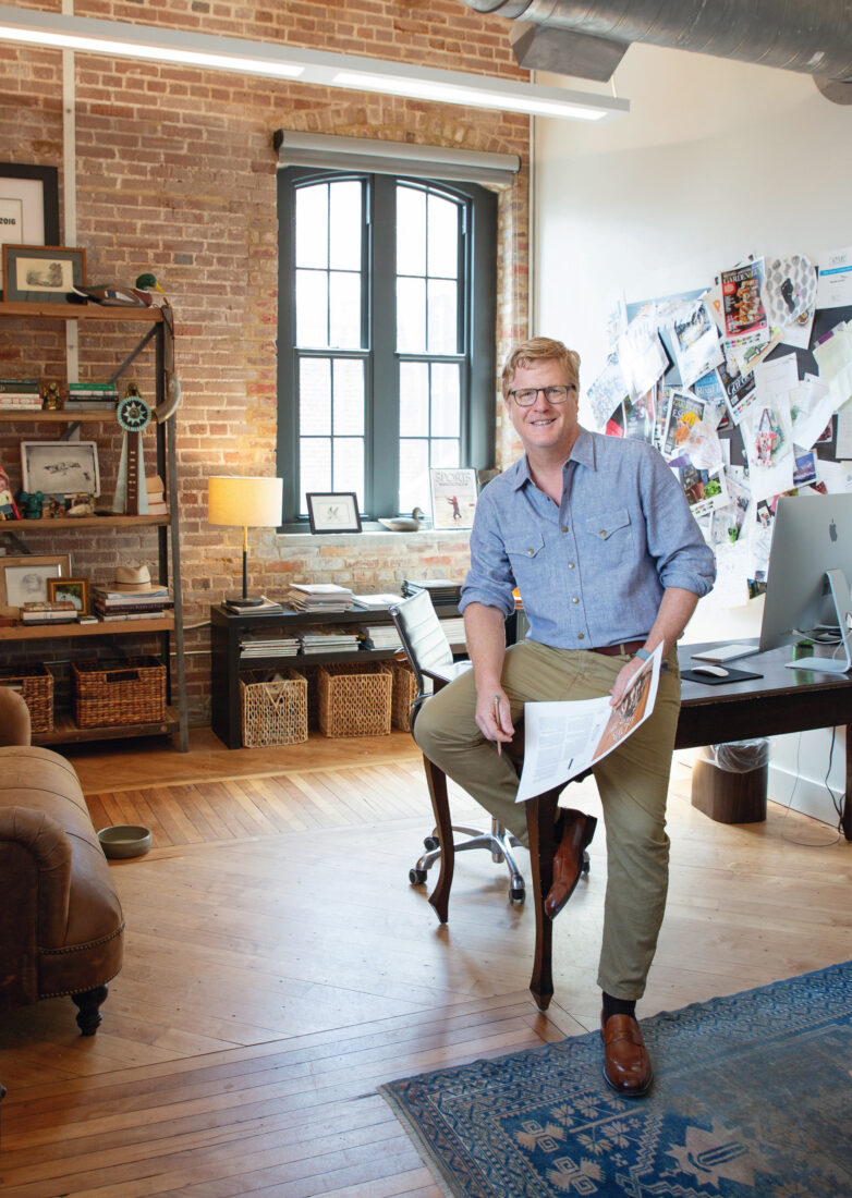 A man sits on a desk in an office