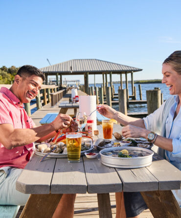 two people dining at a picnic table on a dock