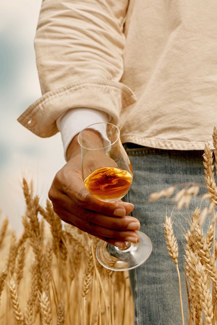 A hand holds a glass of whiskey