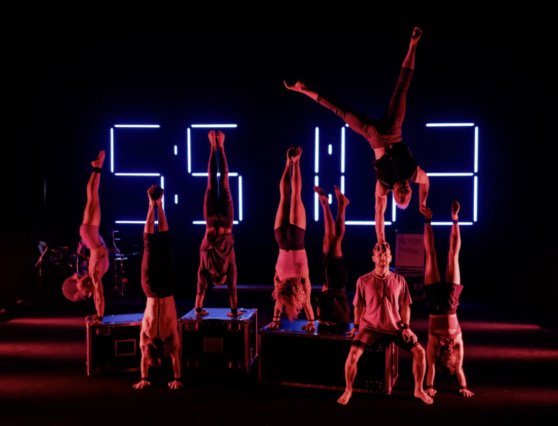 Acrobats on a stage balance in a handstand
