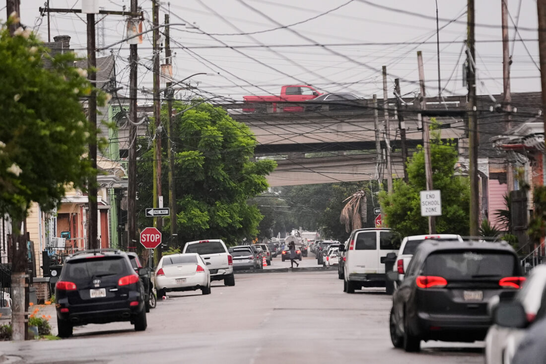 Cars parked along a street with a highway overpass in the distance