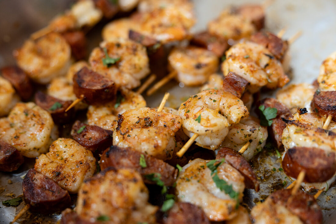 Grilled shrimp and andouille skewers with Cajun spice, and herb oil.