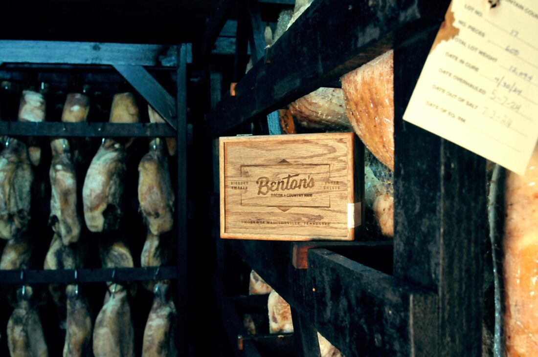 A wood box ina. smokehouse with legs of ham