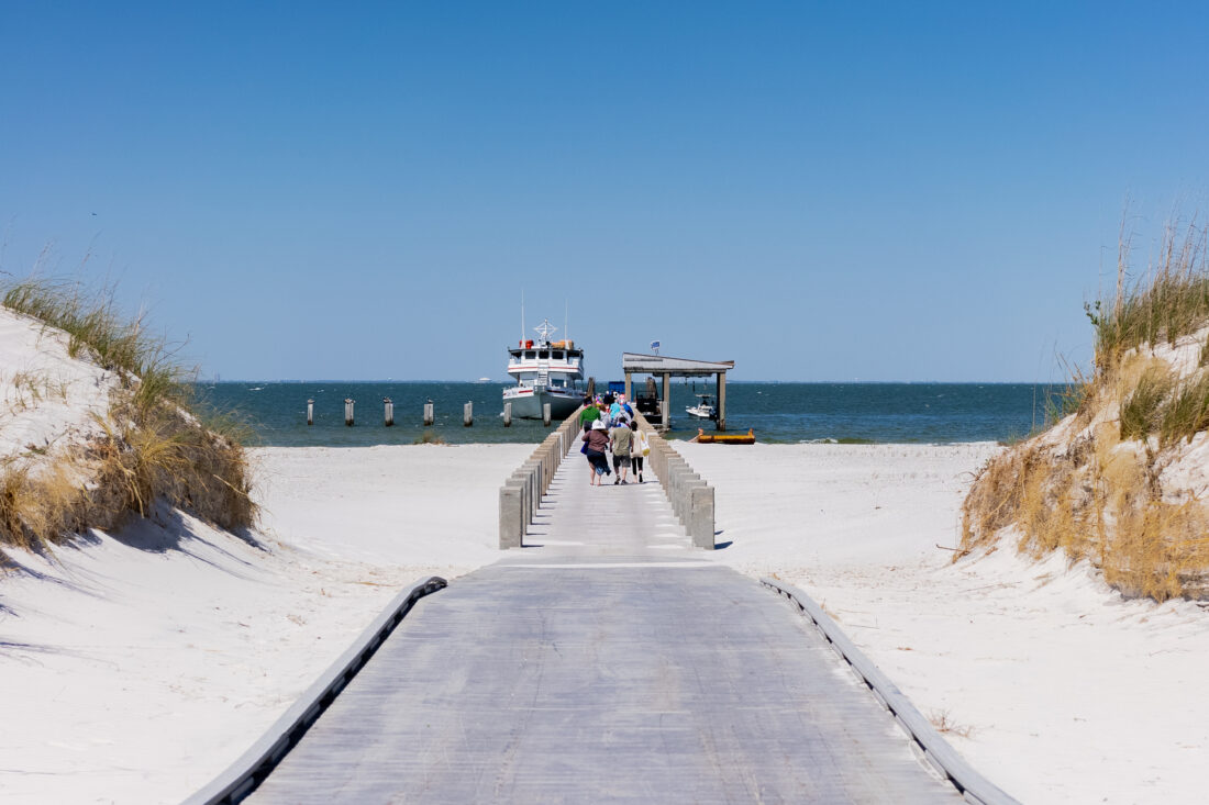 People walk on a beach to a ferry