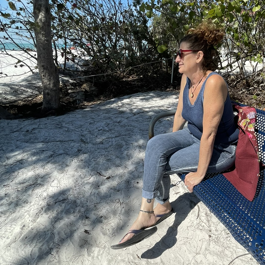 A woman sitting on a bench at the beach