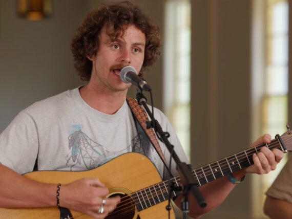 A man singing at a microphone and playing a guitar
