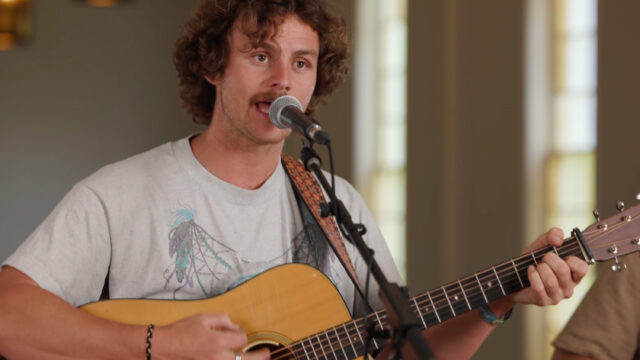 A man singing at a microphone and playing a guitar