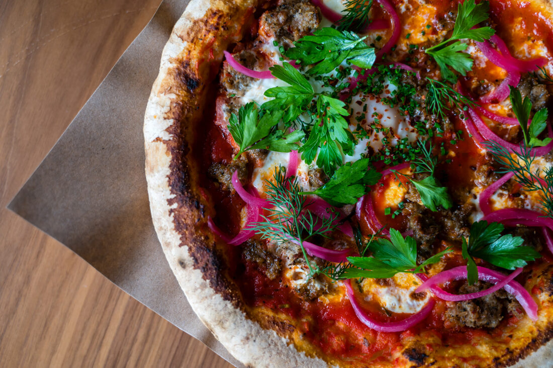 A pizza with pickled red onion