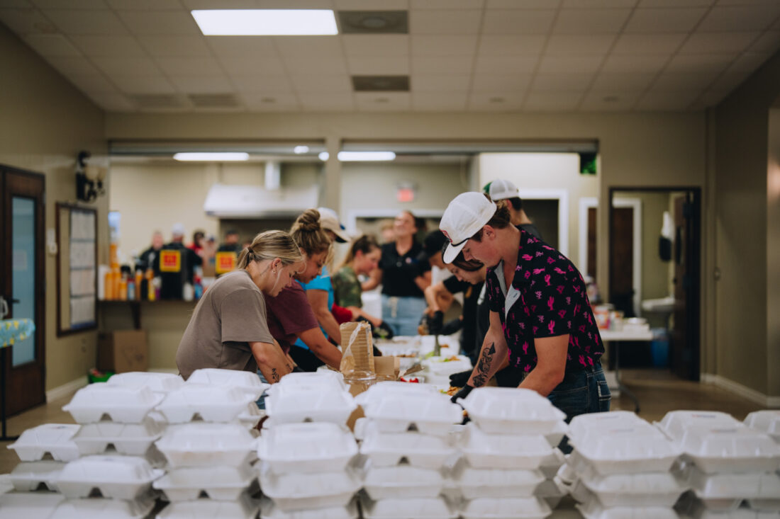 A team of people prepare boxes of meals
