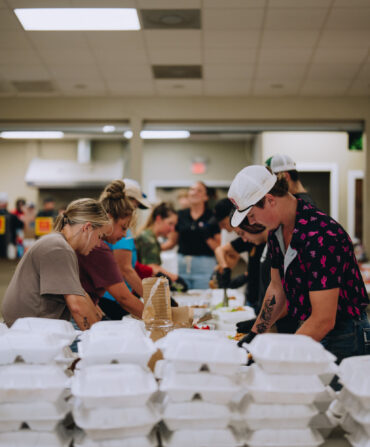 A team of people prepare boxes of meals