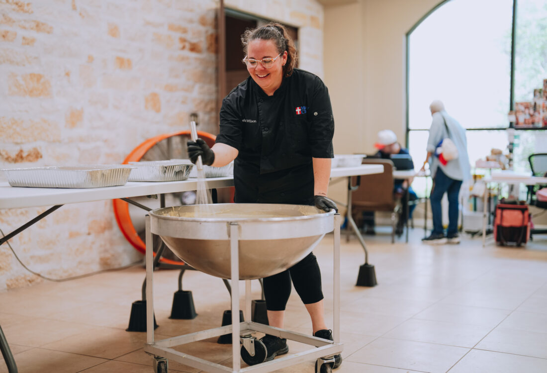 A woman mixes food in an industrial kitchen
