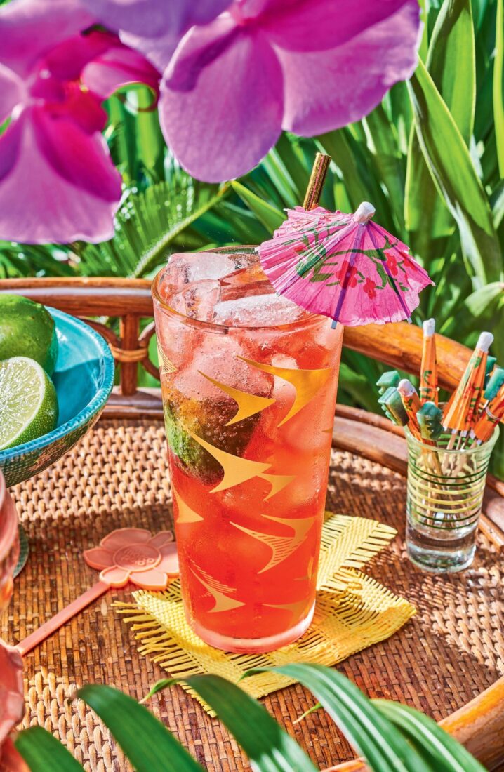 A red cocktail in a tall glass with an umbrella