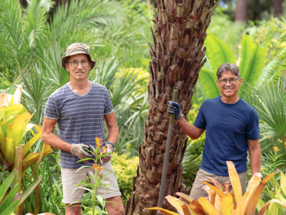 A pair of gardeners stand in a patch of colorful bromeliads