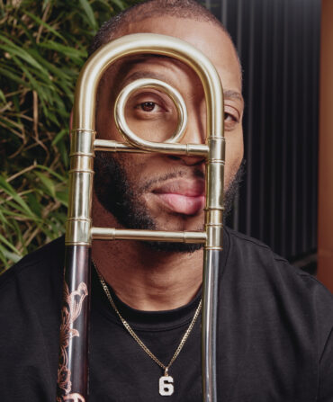 A portrait of a man with a brass instrument in front of his face