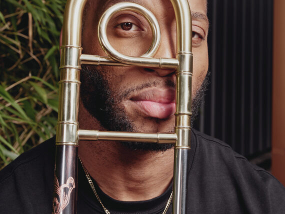 A portrait of a man with a brass instrument in front of his face