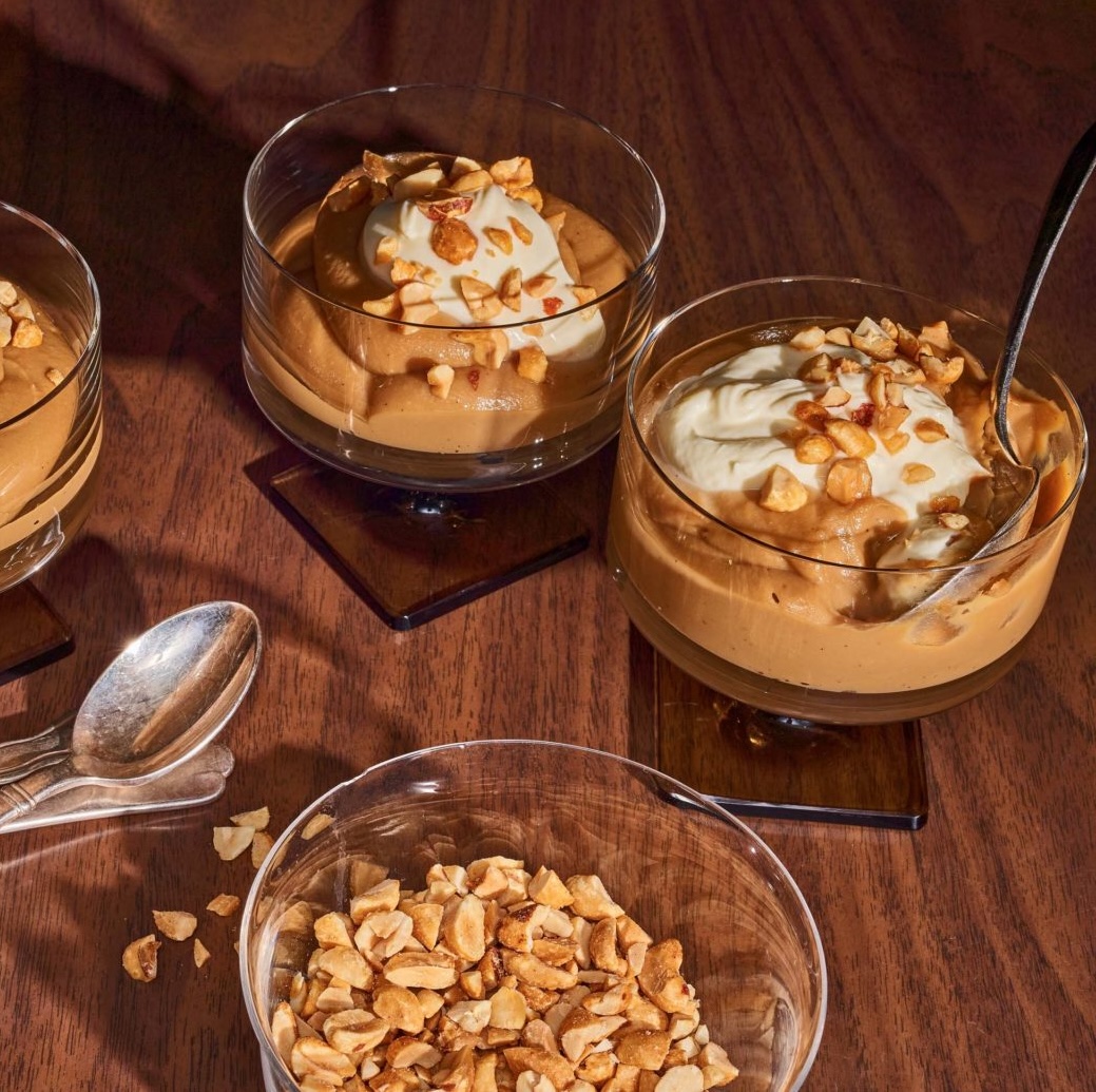 bowls of butterscotch bourbon pudding with whipped cream and peanuts