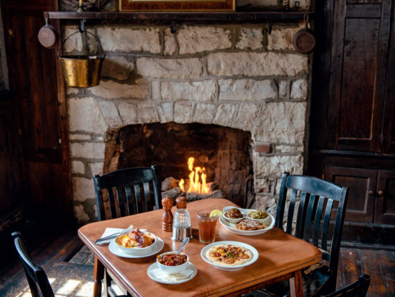 A table with four chairs with dishes next to a stone fireplace